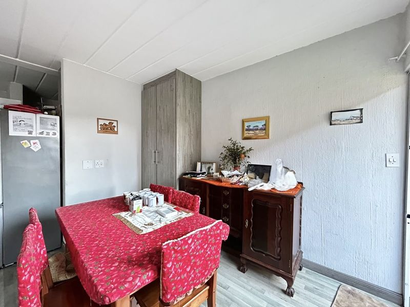 A dining area featuring laminate flooring and a built-in storage cupboard, providing functional space for meals and storage.
