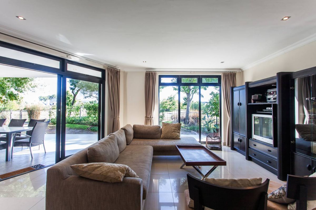 Spacious living room featuring large sliding glass doors that open onto a covered patio, providing ample natural light and garden views.