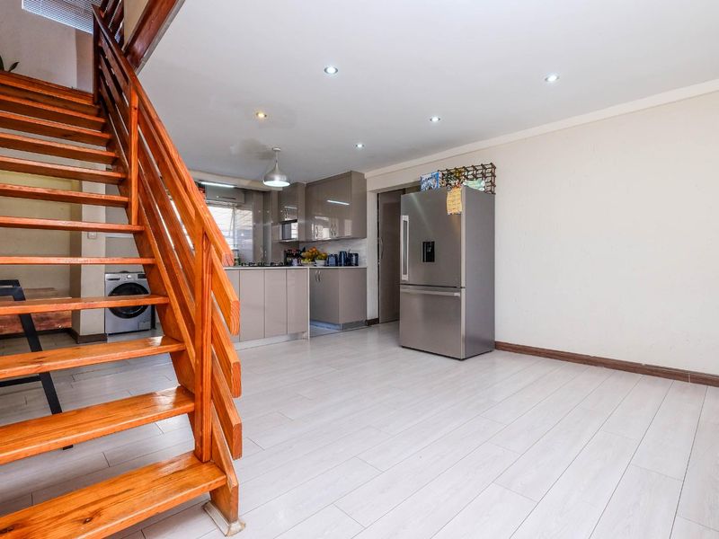 Open-plan living area featuring a modern kitchen with sleek cabinetry and a prominent wooden staircase leading to the upper level.