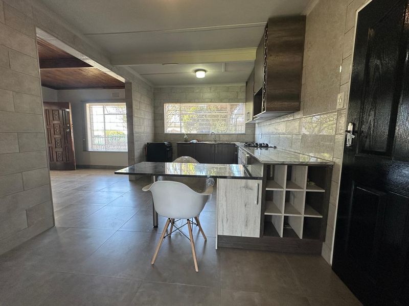 Modern kitchen featuring stone countertops, built-in cabinetry, integrated breakfast bar, and tiled finishes, offering a functional and contemporary cooking space.