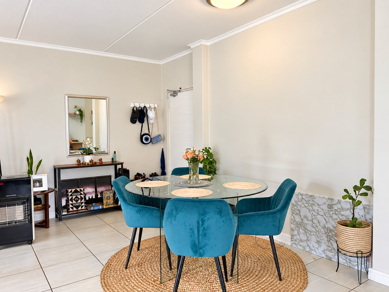 A bright dining area featuring tiled flooring, decorative coving, and a modern marble-effect wall accent panel.