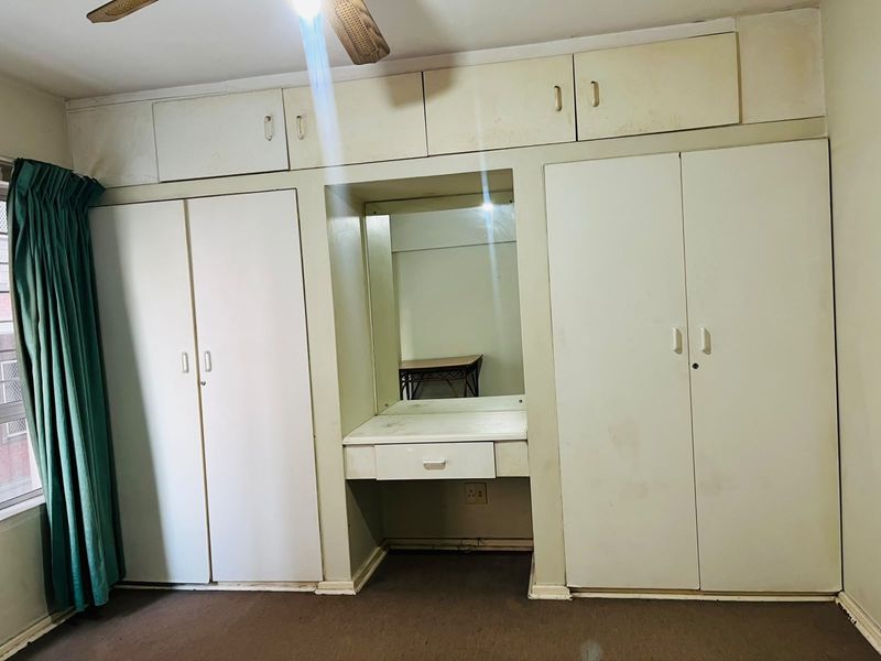 Bedroom featuring extensive built-in cabinetry with integrated vanity and overhead storage, providing ample storage space.