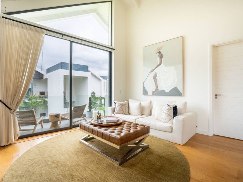 Bright living room featuring high vaulted ceilings, hardwood flooring, and large sliding glass doors that open onto a private balcony.