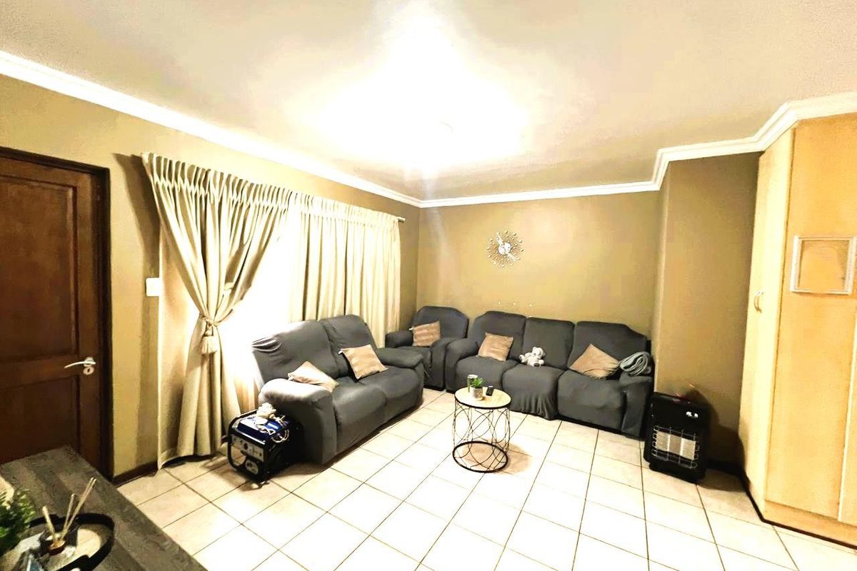 A living room featuring tiled flooring, coved ceilings, and a built-in storage cupboard, providing a functional and neutral living space.