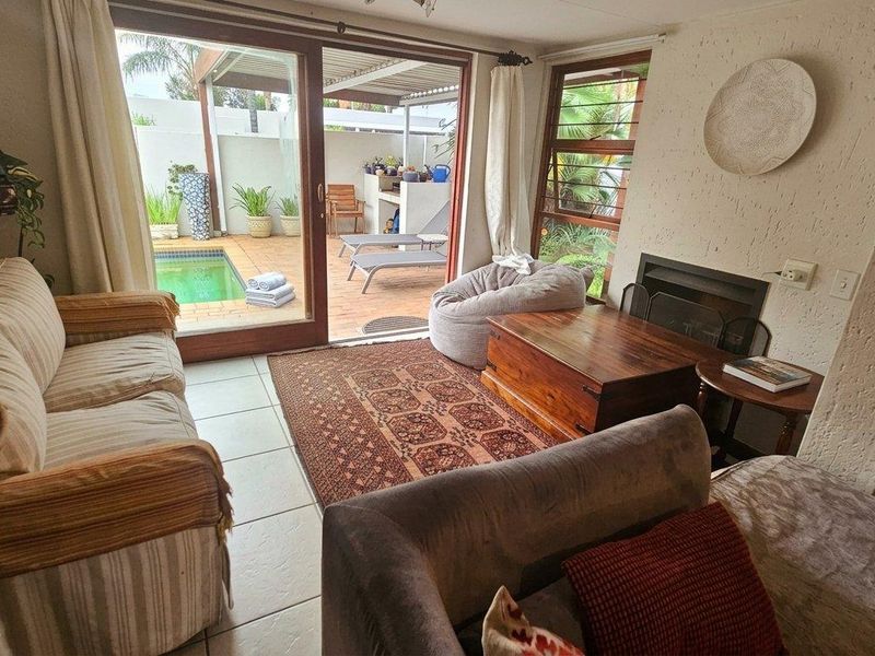 A cozy living room featuring a fireplace and large sliding glass doors that open directly onto a patio and pool area.