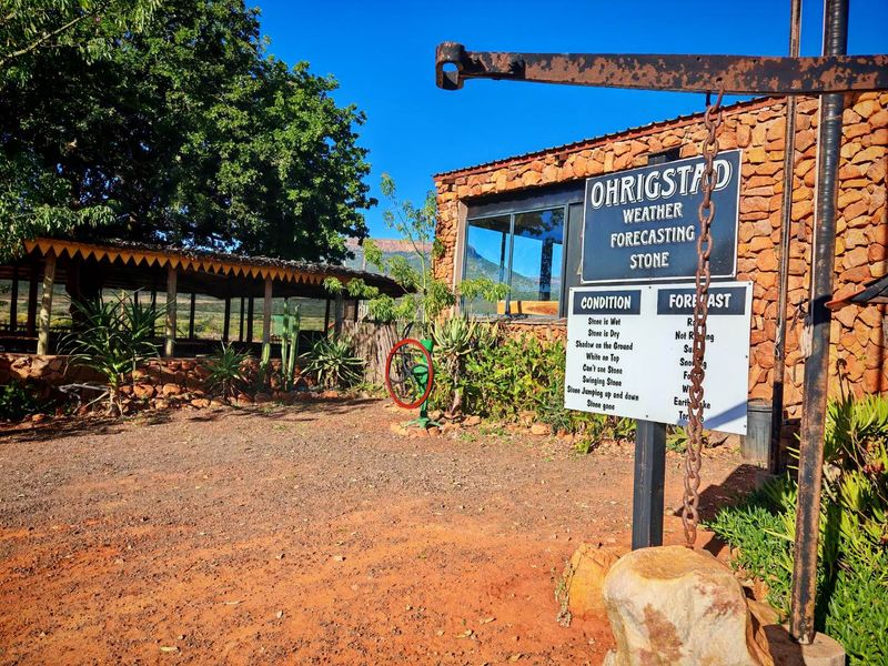 Exterior view of a rustic building featuring stone cladding, a covered patio area, and large glass sliding doors set in a natural landscape.