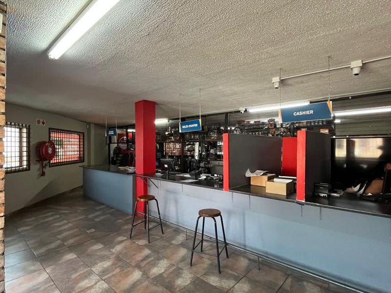 A functional commercial office space featuring a built-in sales counter, tiled flooring, and security-fitted windows, suitable for retail or customer service operations.