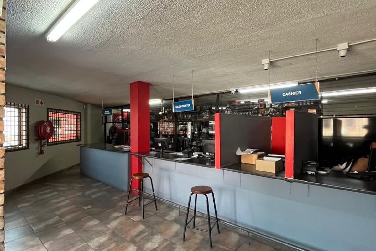 A functional commercial office space featuring a built-in sales counter, tiled flooring, and security-fitted windows, suitable for retail or customer service operations.