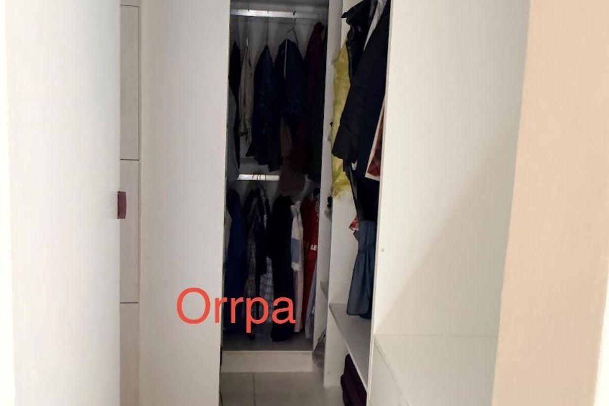 A walk-in closet featuring built-in white cabinetry, shelving, and hanging rails for organized storage.