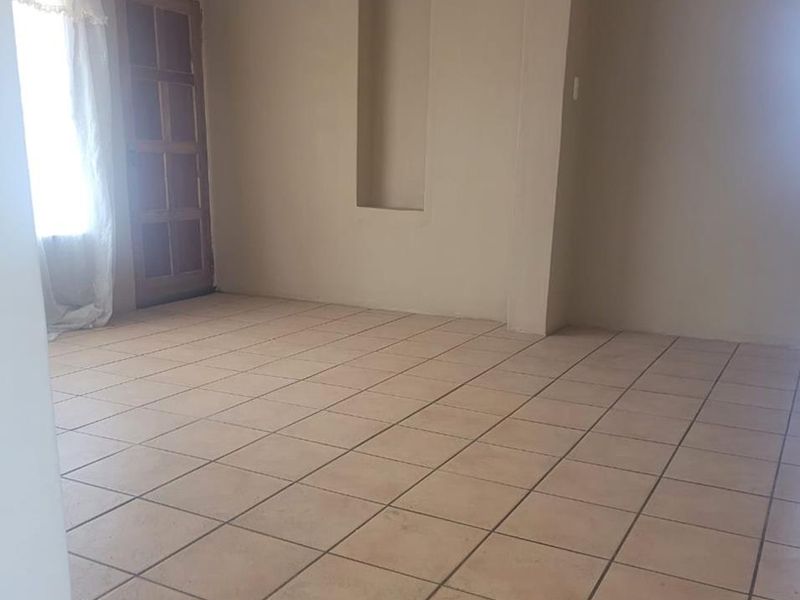 An empty living room featuring neutral wall paint, tiled flooring, and a built-in recessed wall niche.