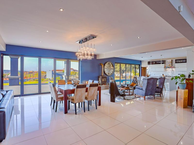 Spacious open-plan living and dining area featuring polished porcelain tiles, modern kitchen with island, and large sliding doors opening to the outdoor patio.