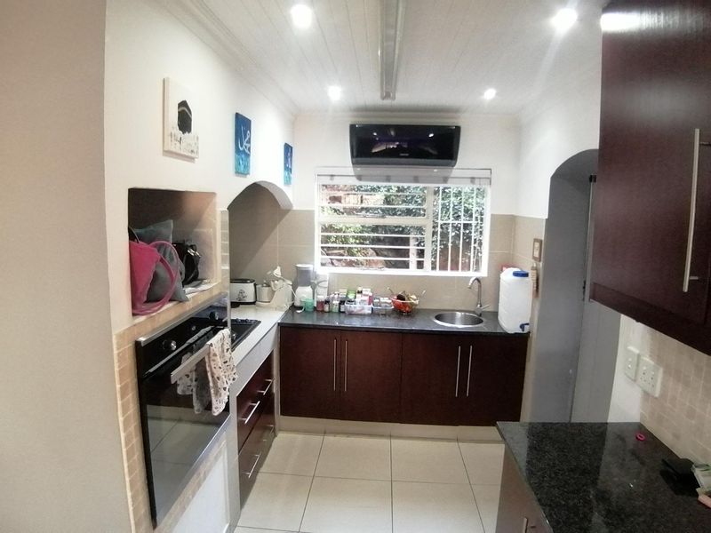 A functional kitchen featuring dark wood cabinetry, granite countertops, a built-in oven, and tiled flooring with recessed lighting.