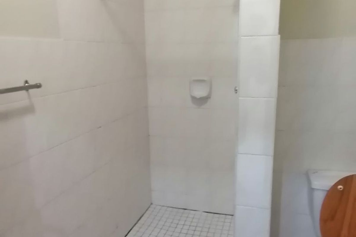 A functional bathroom featuring a tiled shower cubicle with a shower head and a standard toilet.