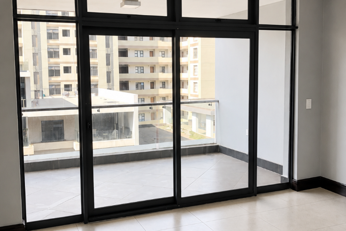 Bright and spacious living area featuring large sliding glass doors that open onto a private balcony with modern tiled flooring throughout.
