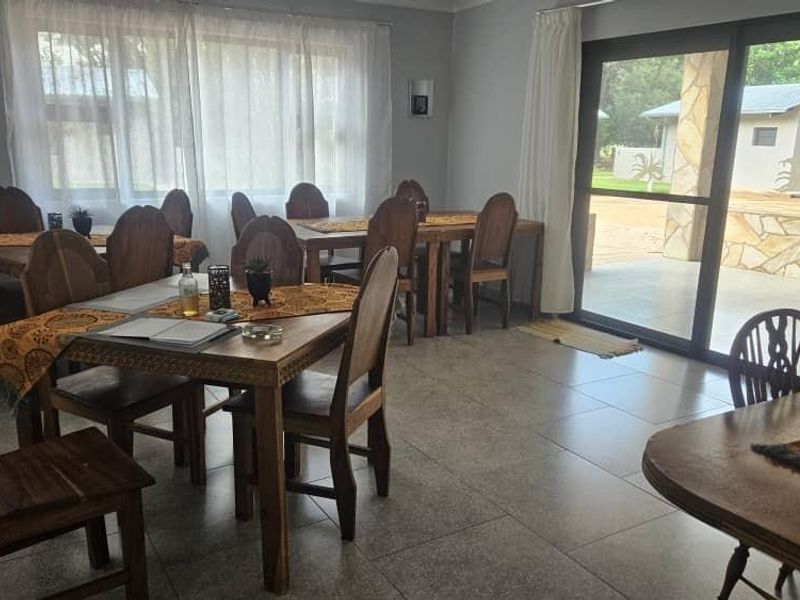 Spacious dining area featuring large windows, tiled flooring, and direct access to an outdoor patio through a sliding glass door.