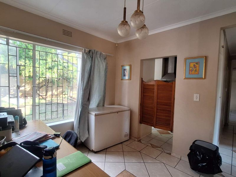 A functional kitchen area featuring tiled flooring, security bars on the window, and classic saloon-style swinging doors leading to the cooking space.