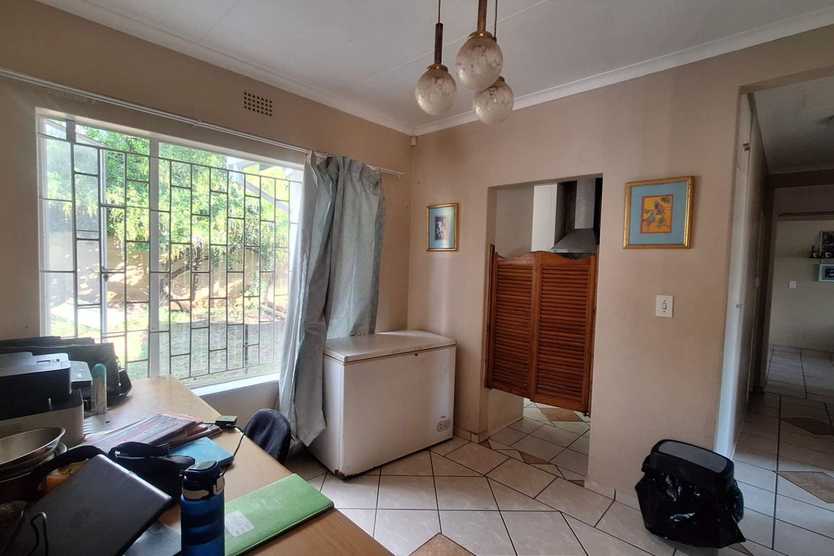 A functional kitchen area featuring tiled flooring, security bars on the window, and classic saloon-style swinging doors leading to the cooking space.