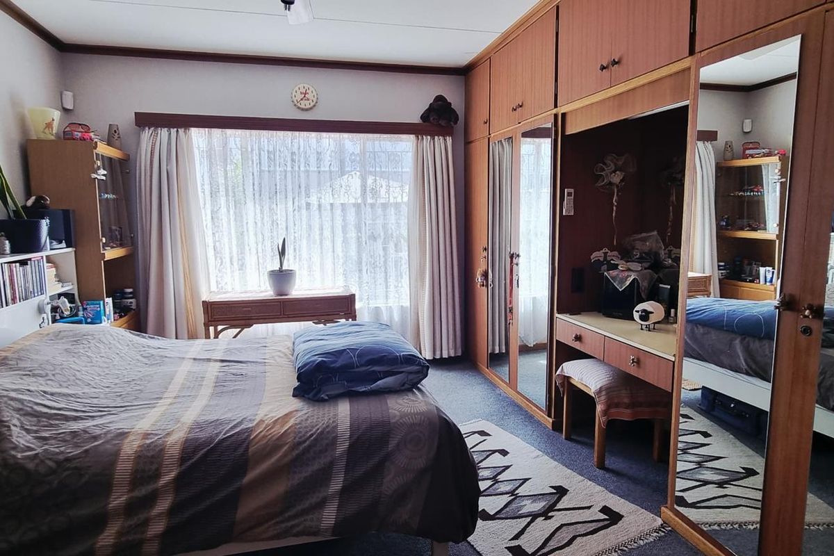 A bedroom featuring extensive built-in wooden cabinetry with integrated mirrored wardrobe doors and a vanity area, providing ample storage space.