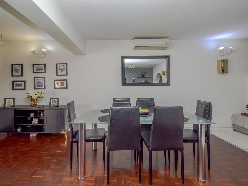 Dining area featuring warm parquet flooring, a wall-mounted split-system air conditioner, and a seamless transition to tiled flooring.
