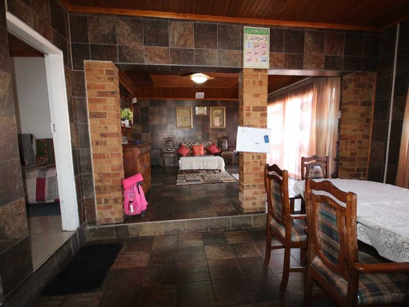Open plan living and dining area featuring slate tile flooring, exposed brick pillars, and timber ceiling finishes.