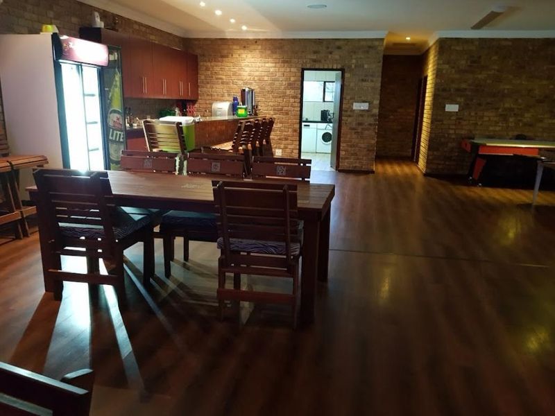 Spacious open-plan entertainment area featuring exposed brick walls, laminate flooring, and a built-in bar, with direct access to a utility area.