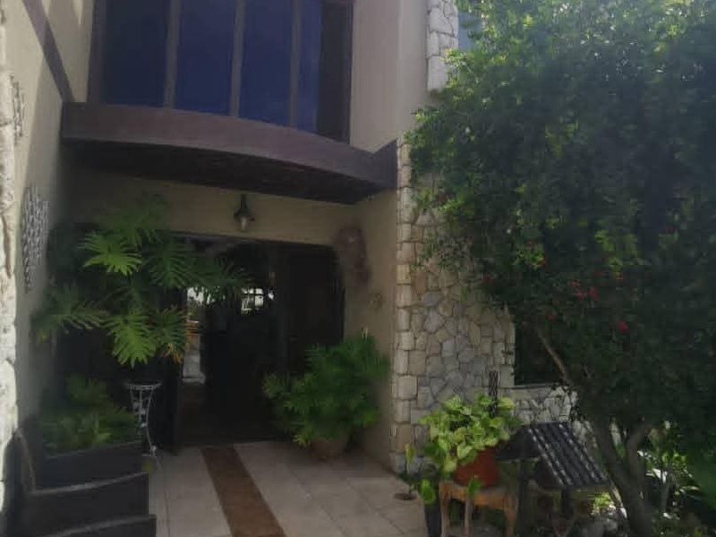 Front entrance of a two-story house featuring stone cladding, a tiled walkway, and large windows under a covered porch area.