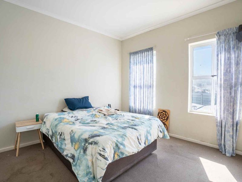 A standard bedroom featuring neutral wall paint, carpeted flooring, and natural light provided by two windows with fitted curtain tracks.
