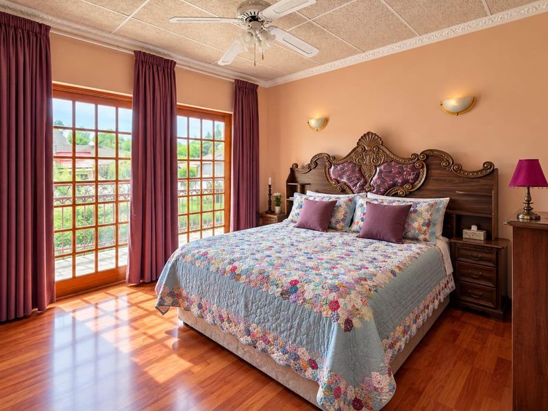 Spacious bedroom featuring laminate flooring, crown molding, a ceiling fan, and double french doors providing access to an outdoor area.