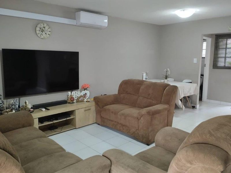 A functional living room featuring tiled flooring and a wall-mounted split-system air conditioning unit.