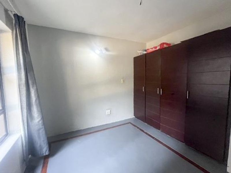 A simple bedroom featuring built-in wooden cupboards and neutral wall finishes, offering a clean and functional space ready for personalization.