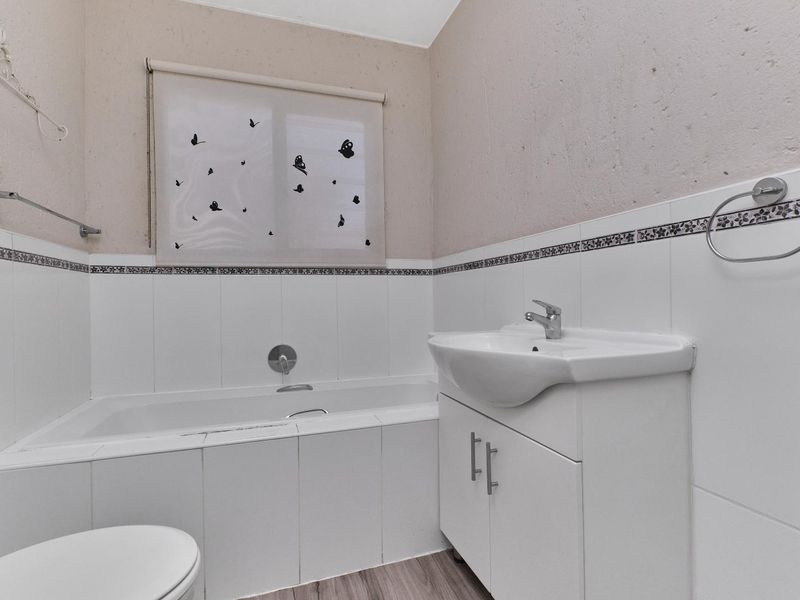A functional bathroom featuring a built-in vanity with basin, a tiled bathtub surround, and neutral wall finishes.