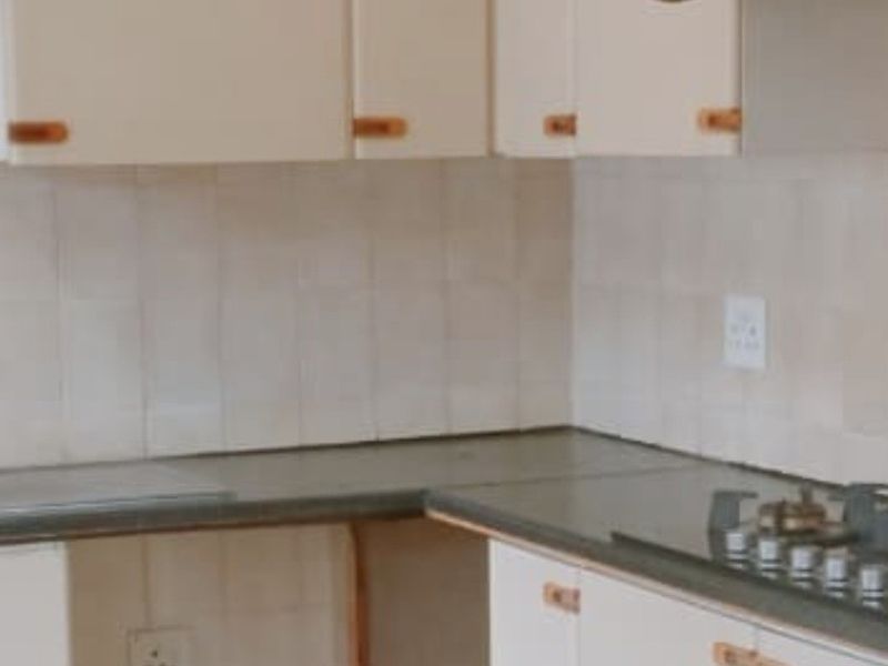 A dated kitchen featuring built-in cabinetry, a gas hob, and an extractor fan, currently requiring cosmetic updates and repairs to the cabinetry.