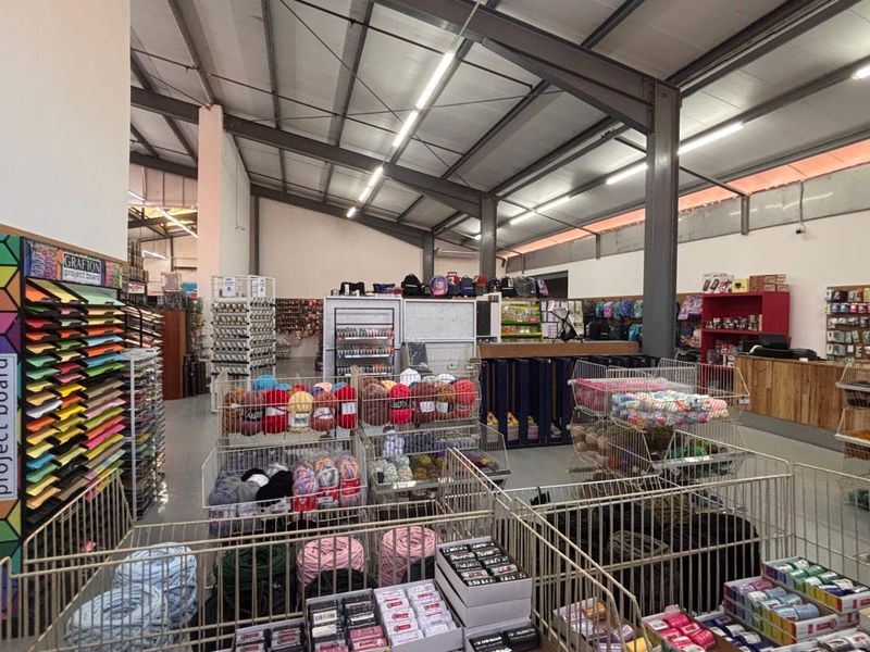 Spacious retail interior featuring an open-plan layout with exposed steel structural beams, industrial lighting, and durable concrete flooring.