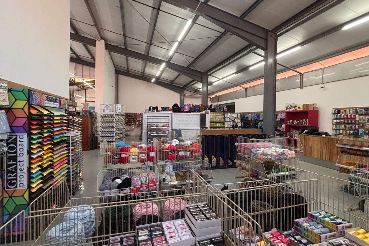 Spacious retail interior featuring an open-plan layout with exposed steel structural beams, industrial lighting, and durable concrete flooring.