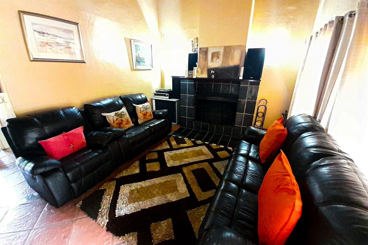 A living room featuring a tiled fireplace surround and terracotta floor tiles, creating a warm and traditional atmosphere.