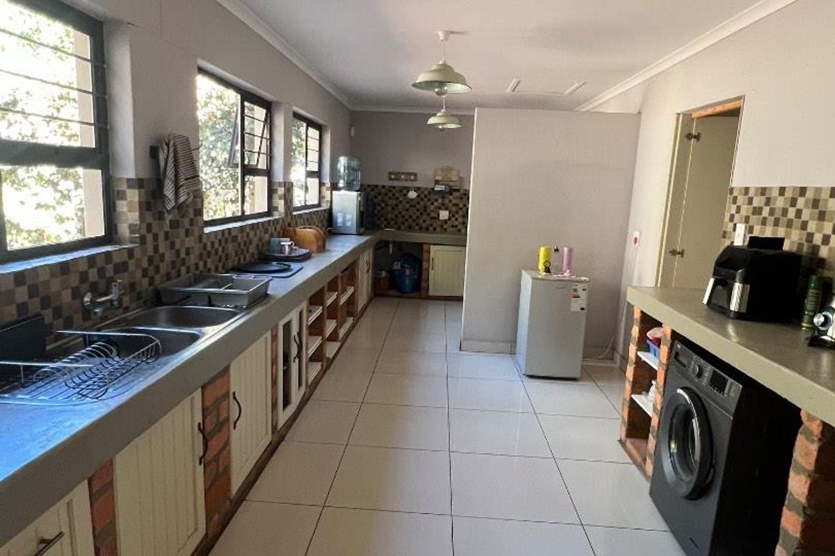 A spacious, functional kitchen featuring extensive concrete countertops, brick-based cabinetry, tiled flooring, and multiple windows providing ample natural light.