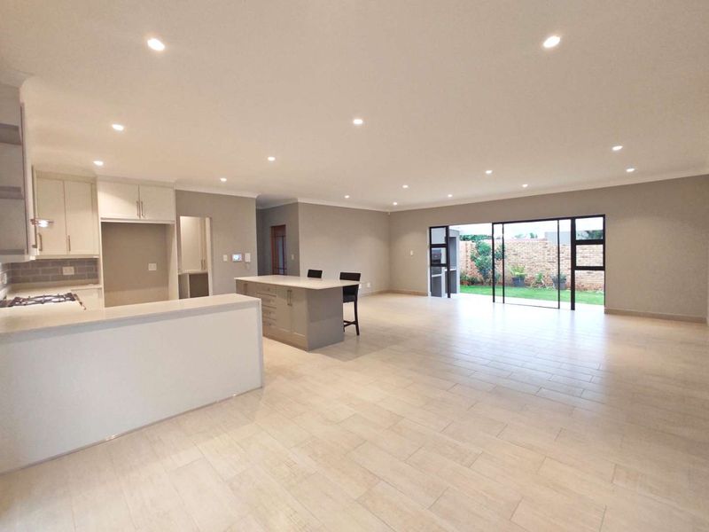 Spacious open-plan living area featuring a modern kitchen with a central island, sleek cabinetry, and large sliding doors opening to the rear garden.