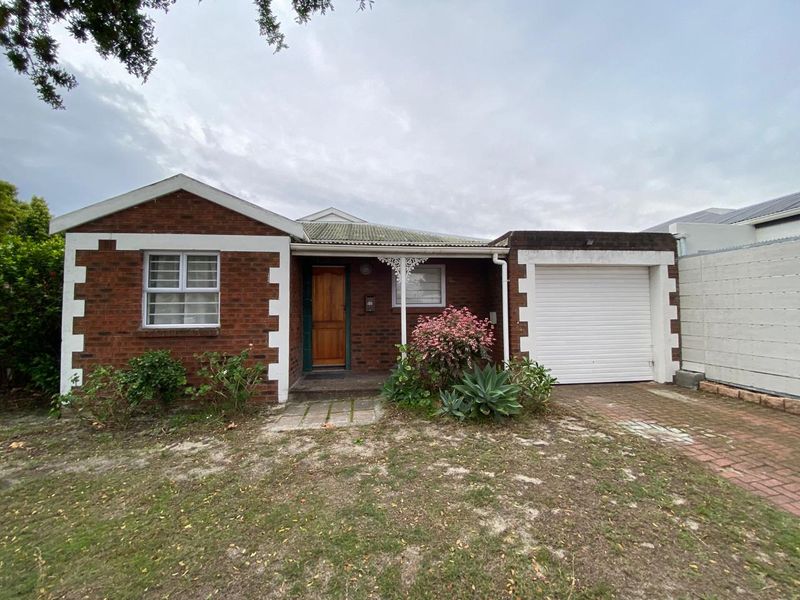 Front elevation of a single-story brick house featuring a single garage, tiled roof, and a covered entrance porch.