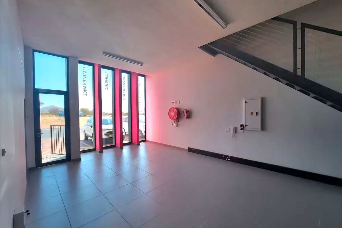 A spacious, empty entrance area featuring tiled flooring, large vertical windows, and a staircase, suitable for a professional office or commercial reception space.