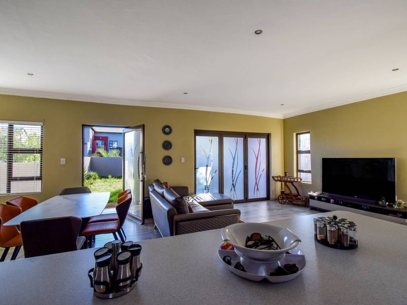 Spacious open-plan living and dining area featuring tiled floors, recessed lighting, and direct access to the rear garden through sliding glass doors.