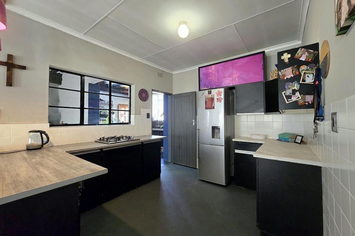 Functional kitchen featuring dark cabinetry, gas hob, laminate countertops, and tiled splashbacks with a practical layout and direct access to an adjacent utility area.