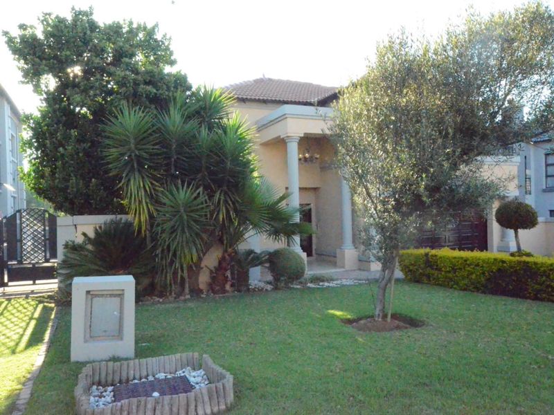 Front elevation of a residential house featuring a covered entrance with concrete columns, a well-maintained front garden, and a paved driveway.
