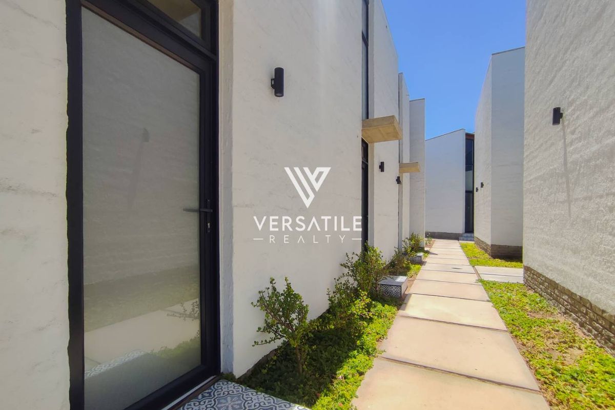 A modern exterior walkway featuring clean white walls, paved paths, and integrated lighting, providing a sleek and contemporary aesthetic for the townhouse property.