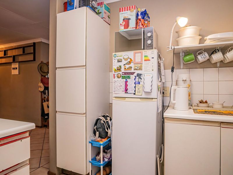 A functional kitchen area featuring built-in cabinetry, a tiled backsplash, and a dedicated pantry cupboard, providing practical storage and workspace.