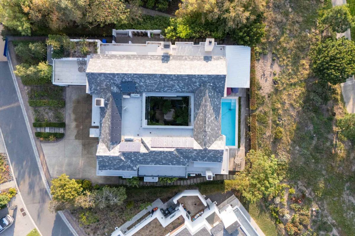 Aerial view of the property showcasing the roof layout, central courtyard, swimming pool, and surrounding landscaped grounds.