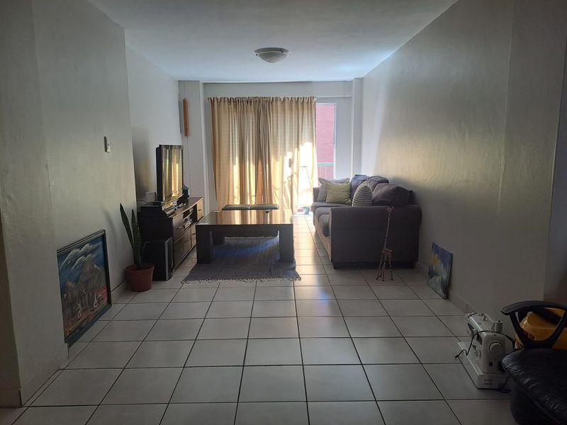 A functional living room featuring ceramic tile flooring and a sliding glass door providing access to the exterior.