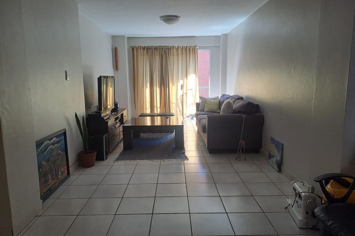 A functional living room featuring ceramic tile flooring and a sliding glass door providing access to the exterior.