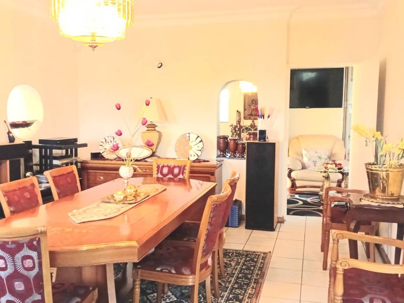 A dining room featuring tiled flooring, an arched doorway leading to an adjacent space, and decorative ceiling cornice.