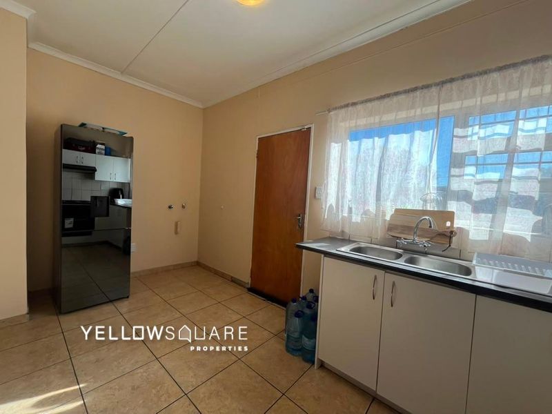 A functional kitchen area featuring tiled flooring, built-in cabinetry, and a double basin sink with a window view.