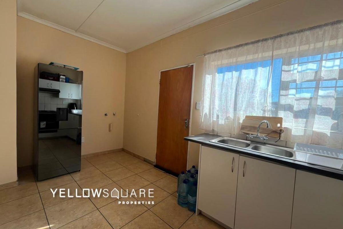 A functional kitchen area featuring tiled flooring, built-in cabinetry, and a double basin sink with a window view.